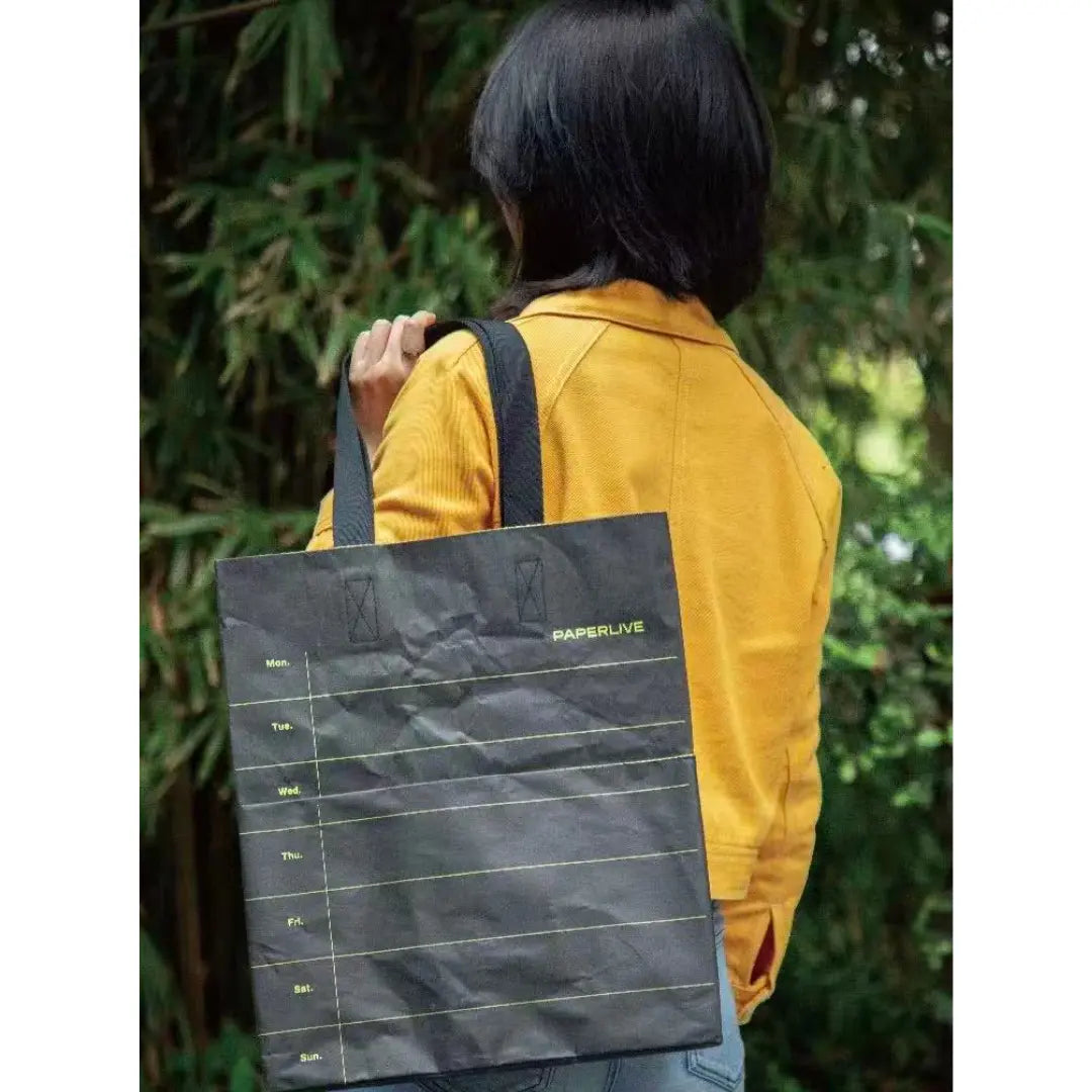 Black washable paper tote bag carried by hand for branded merchandise.